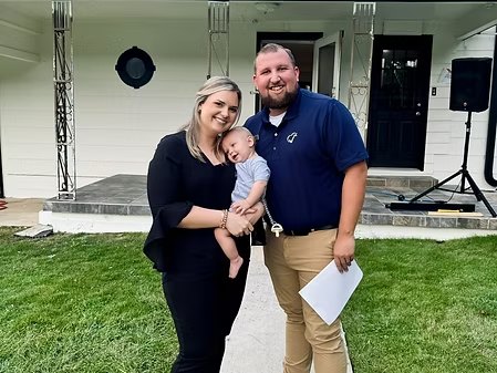 Logan and Brittany LeGrande with their baby in front of the Hope House porch