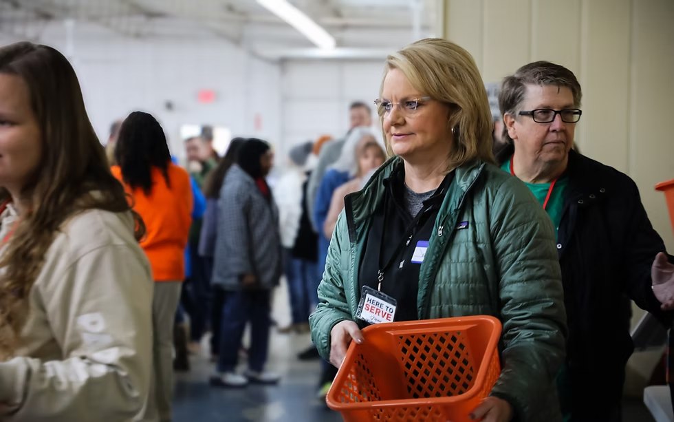 Volunteer with a Here to Serve badge carrying a basket