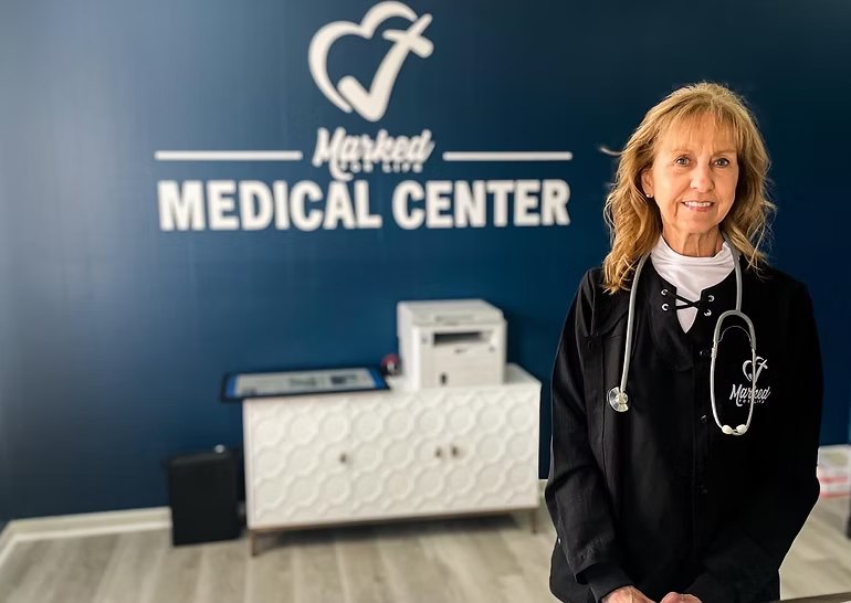 A nurse in a Marked For Life jacket standing in front of the Medical Center sign