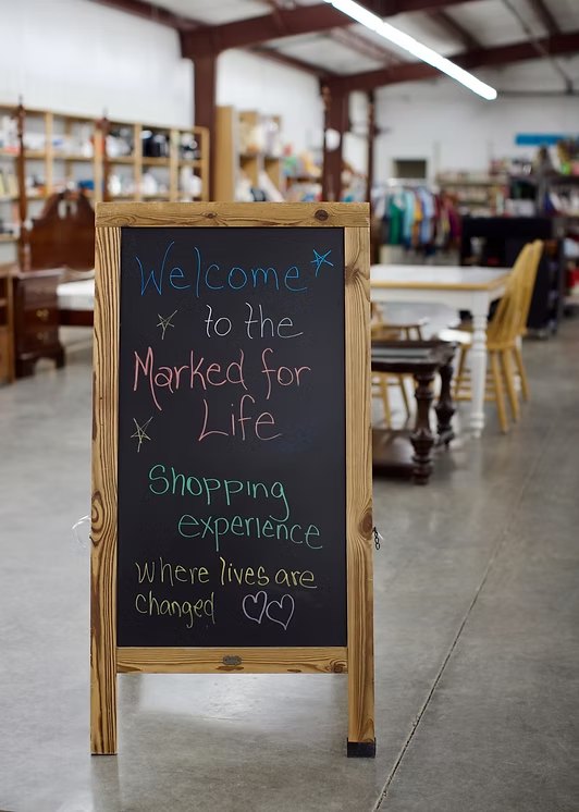 Chalkboard welcome sign inside the Marked For Life Thrift Store