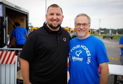 Logan LeGrande with a volunteer at an outdoor Deliver Hope event