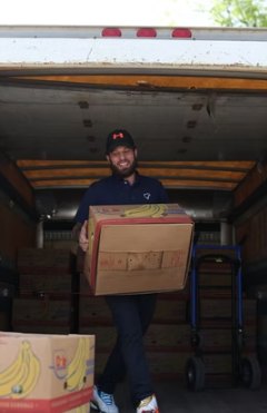 Volunteer carrying a box of bananas from the food rescue truck