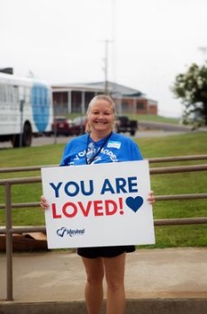 Volunteer holding a You Are Loved sign